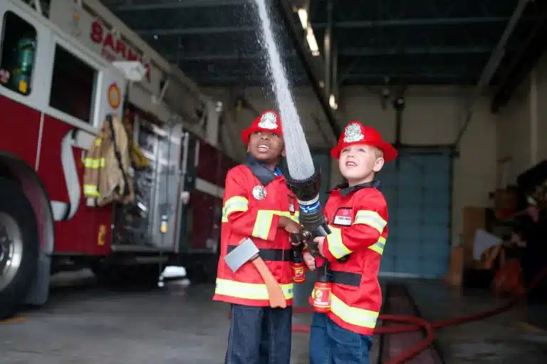 Twee jongetjes met een brandweerpak kostuum aan