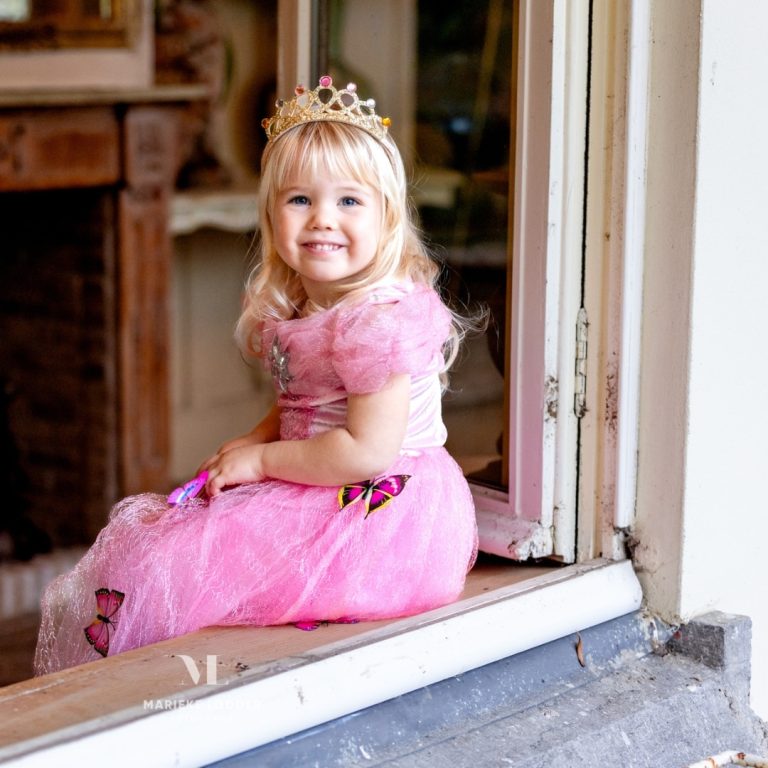 Meisje met een roze prinsessenjurk aan en bijpassende accessoires